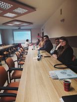 Uczestnicy spotkania siedzący przy blacie stołu.