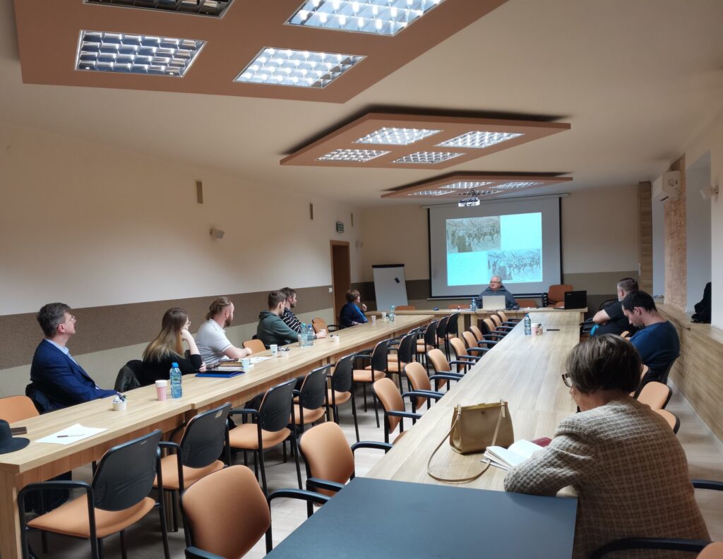 Wszyscy uczestnicy spotkania przy stolikach ustawionych w podkowę.