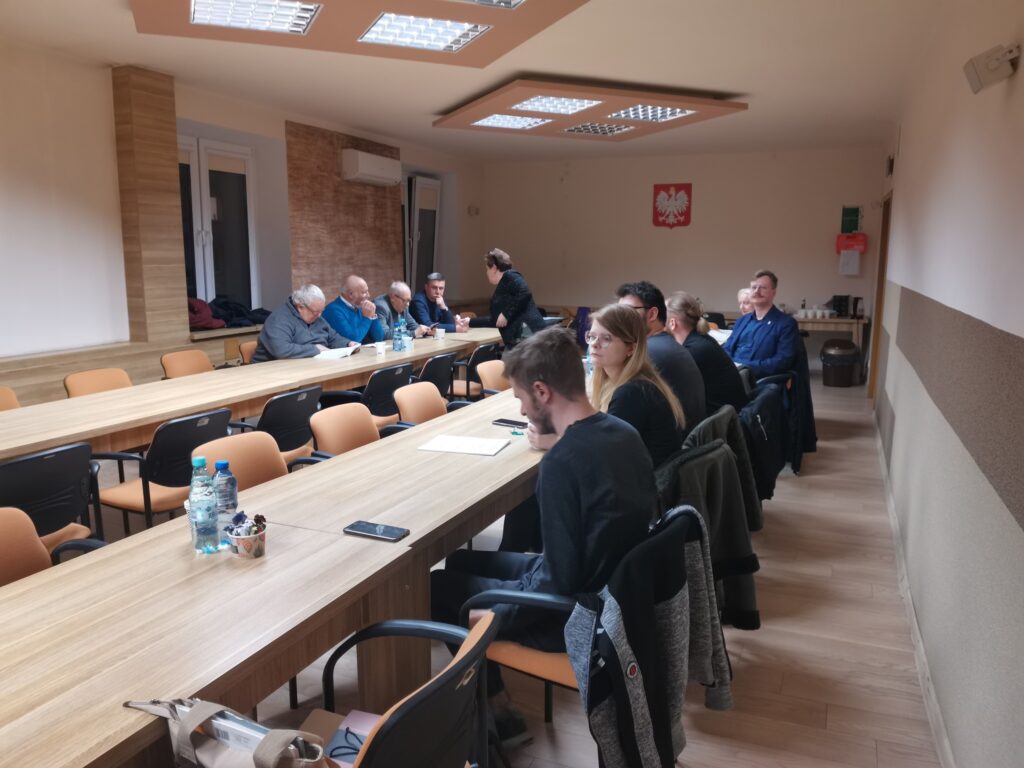 Uczestnicy spotkania przy stolikach ustawionych w podkowę.