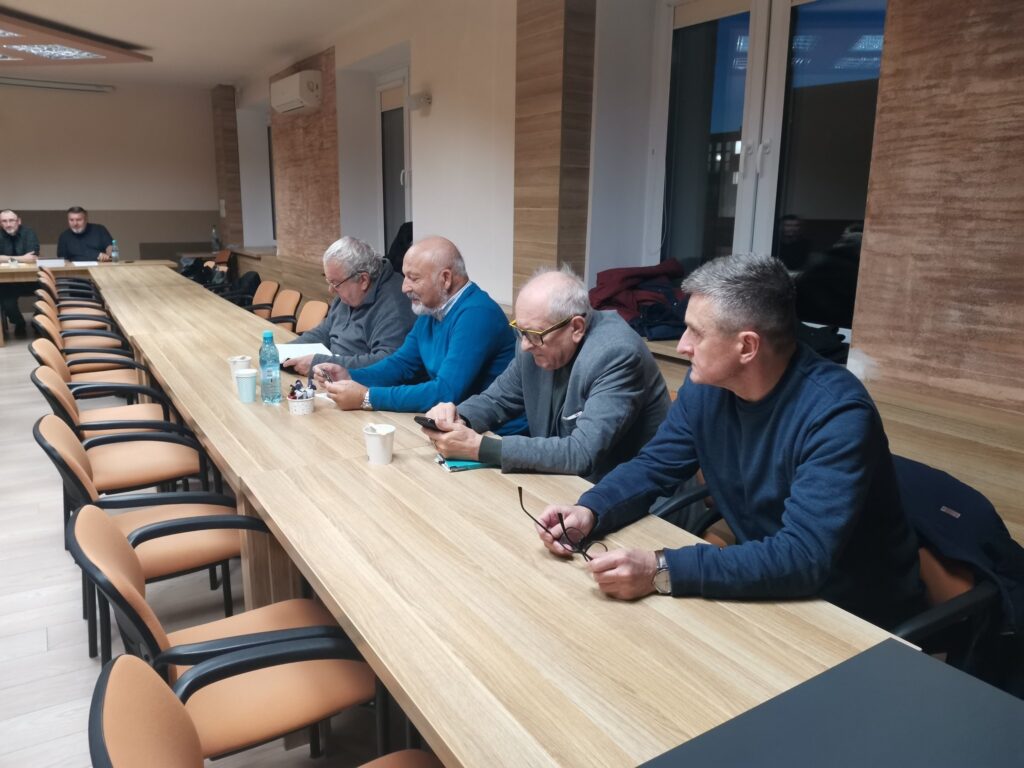 Uczestnicy spotkania przy stolikach ustawionych w podkowę.