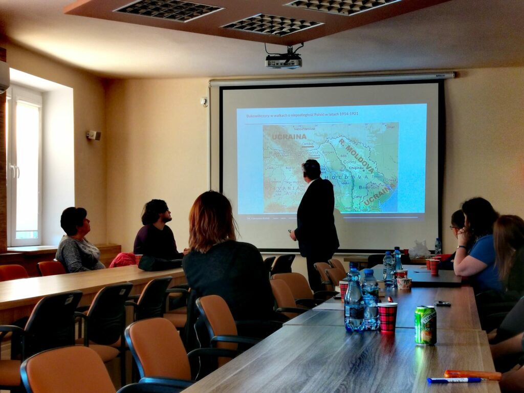 Prelegent i uczestnicy spotkania, na pierwszym planie mapa.