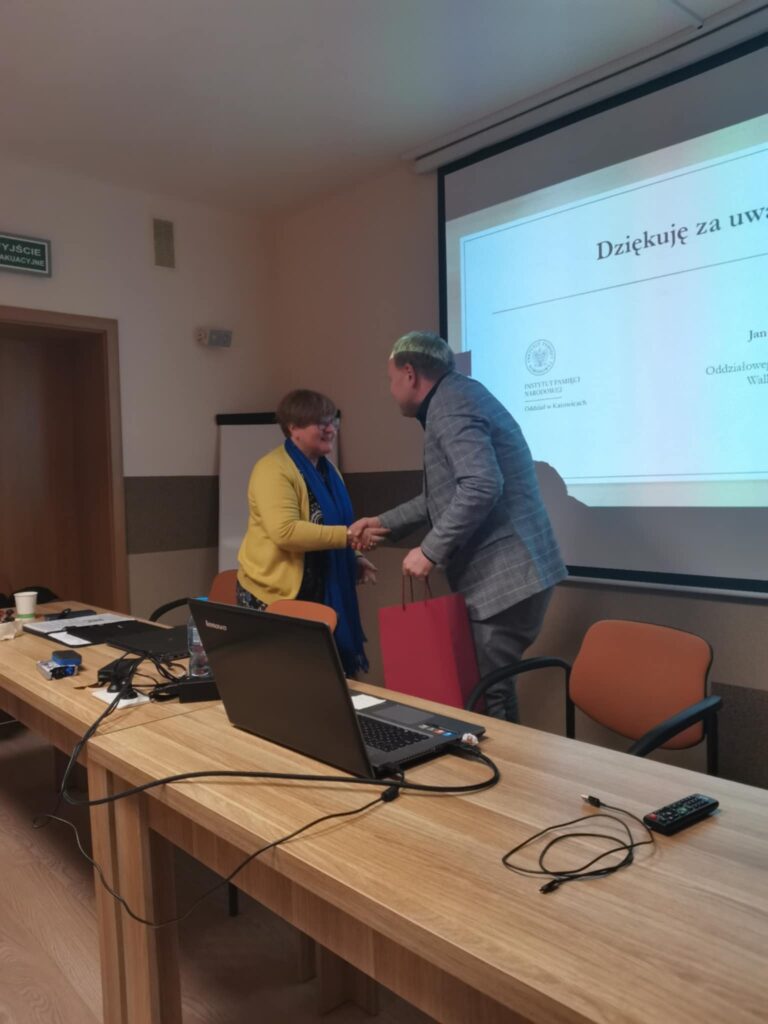 Prezes Julia dziwoki wręcza prelegentowi upominek.